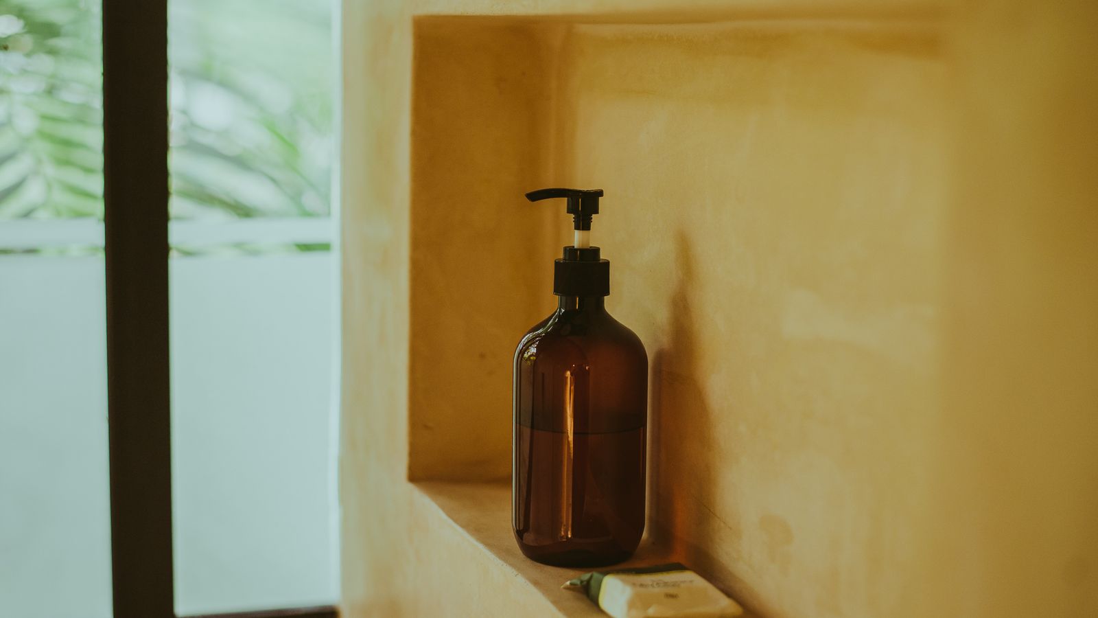 An amber bottle and a bar of soap on a stone bathroom shelf